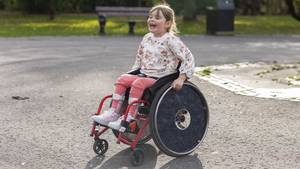 Fröhlich lachendes Mädchen im Rollstuhl