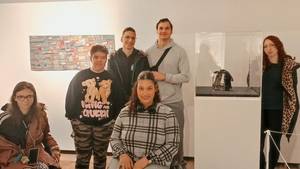 Gruppenfoto unserer Schüler:innen im Textilmuseum stehen neben einem Kunstwerk im Glaskasten.